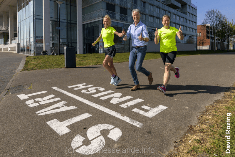 Hardlopers opgelet! Een parcours afleggen kan gewoon in de wijk. Er is een route van bijna 2 kilometer uitgestippeld. Sinds kort staan in het Gerrit Rietveldpark grote cijfers op de weg: een circuit van 1.900 meter met een duidelijke start en finish, en ertussen om de 100 meter cijfers met de afstand. ’Een makkelijke manier om te trainen’, vertelt Saskia Warmer van Loopgroep Nesselande. Samen met een sporter van atletiek- en triatlonvereniging Trackstars Nesselande diende ze een bewonersinitiatief in voor de route, die onder andere via het Korfoepad loopt. ‘Het is een mooie stimulans voor alle Nesselanders om te gaan rennen. Ze kunnen het parcours zelf gebruiken. En voor de trainingen van onze hardloopgroep en Trackstars is het superfijn. We hebben al een kleiner parcours en met deze nieuwe route is ons trainingsgebied verbeterd.' Blijven fit Van beginnend hardloper tot marathonloper: iedereen kan trainen bij de loopgroep bij de Zevenhuizerplas. ‘Mensen kennen ons wel; we rennen wekelijks met zóveel lopers met gele hesjes aan door de buurt’, vertelt Saskia. ‘We hebben trainers in dienst en gebruiken een handig muntensysteem. Doe je mee, dan kost het 1 muntje van 3,50 euro. Je hoeft dus geen lid te zijn. Ideaal toch? Mijn man en ik regelen alles rondom de loopgroep. We zijn gepensioneerd en hoeven er niet veel aan te verdienen. En we blijven er zelf fit bij natuurlijk.’ Sportboulevard Het parcours is helemaal op z’n plaats in Nesselande, vindt Saskia. ‘Nesselande is een enorme sportwijk. De Kosboulevard kun je met het sportpark en de skatebaan een sportboulevard noemen. En kijk maar eens naar de Zevenhuizerplas: we joggen er continu omheen met z’n allen.’
